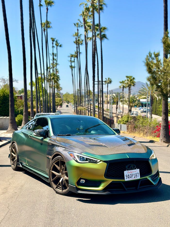 An Infiniti Q60 in a Green Car Wrap Parked on a Street with Palm Trees